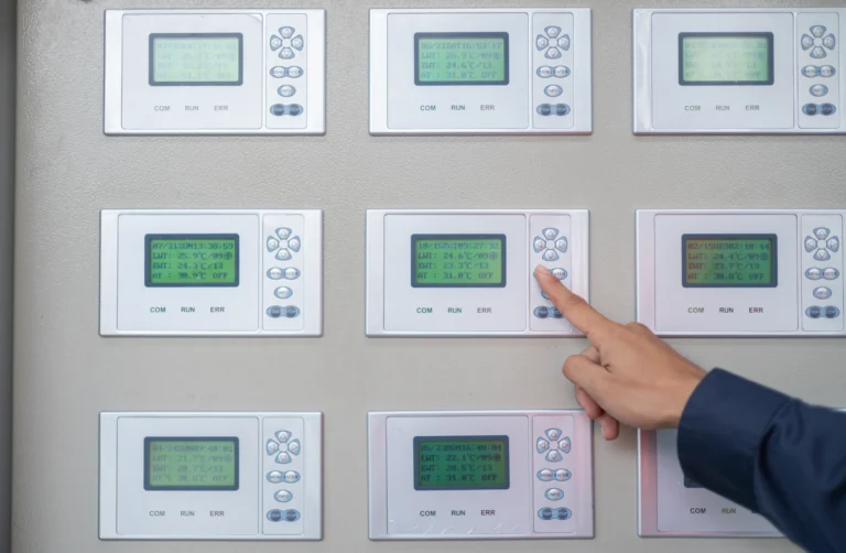 Technician adjusting a building automation system control panel monitoring multiple HVAC zones