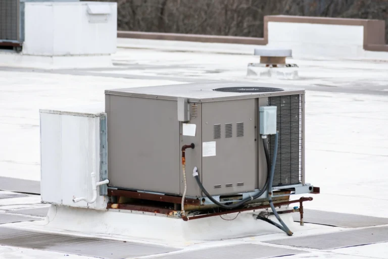 Aging commercial rooftop unit showing rust along the base rail and curb, a common sign the unit needs replacement