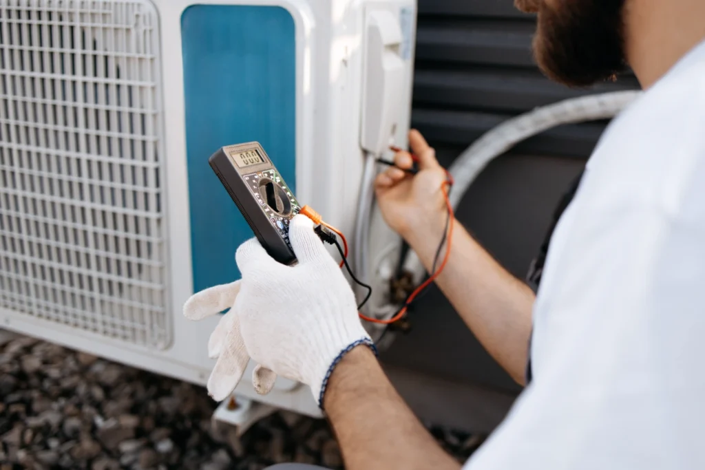 Technician using a multimeter to test voltage on an outdoor AC unit during repair and diagnostics in Midland, TX