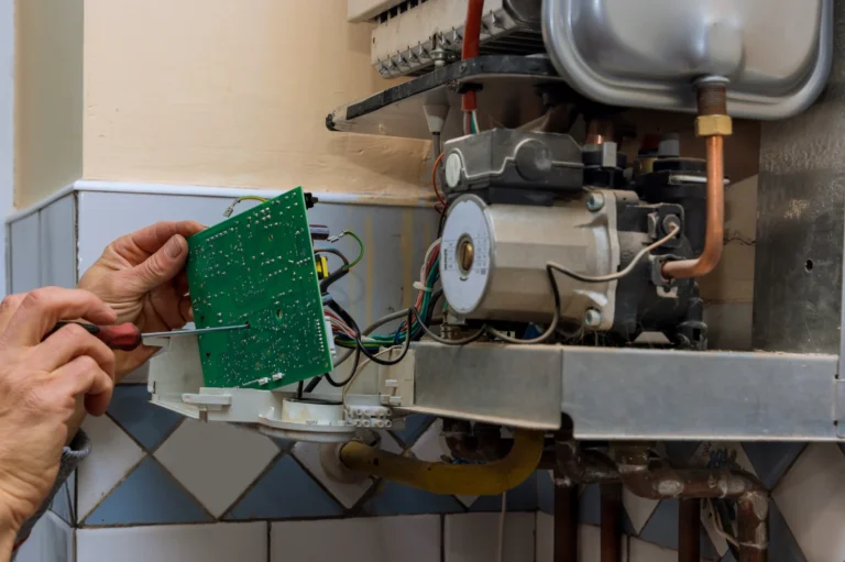 A technician removing a failed control board from a gas fired boiler during a heating system repair.