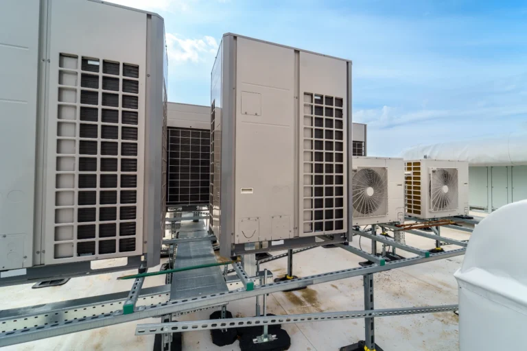Row of commercial HVAC condensing units mounted on steel rails on a flat commercial building rooftop