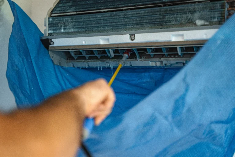 Grimy evaporator coil fins being cleaned inside a residential AC unit with a catch sheet in place