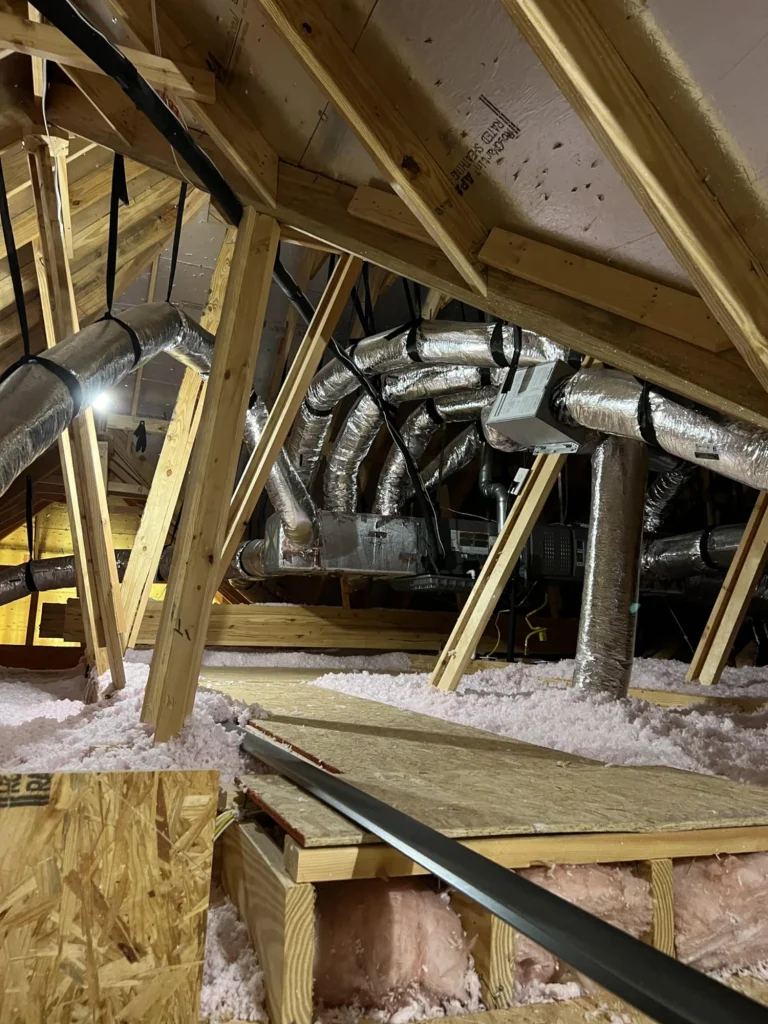 Flex ductwork in an attic with wide-radius bends and strap hangers running from a supply plenum to an air handler